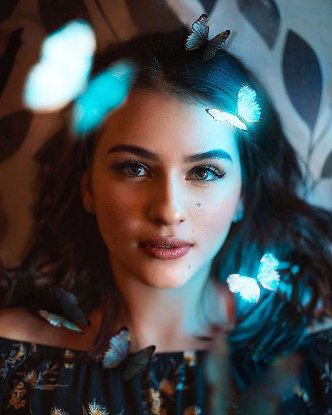 Beautiful girl with glowing butterflies around her face